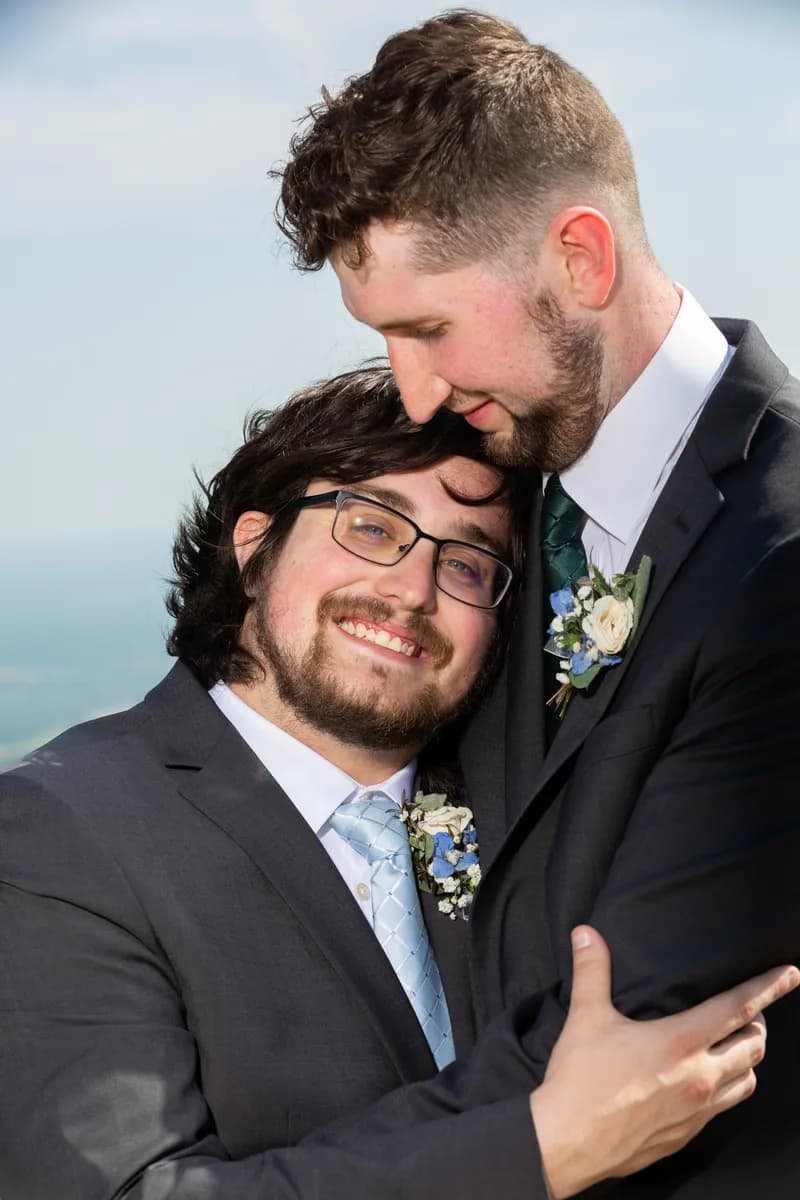 Two grooms sharing a quiet embrace after their Arkansas mountaintop wedding ceremony