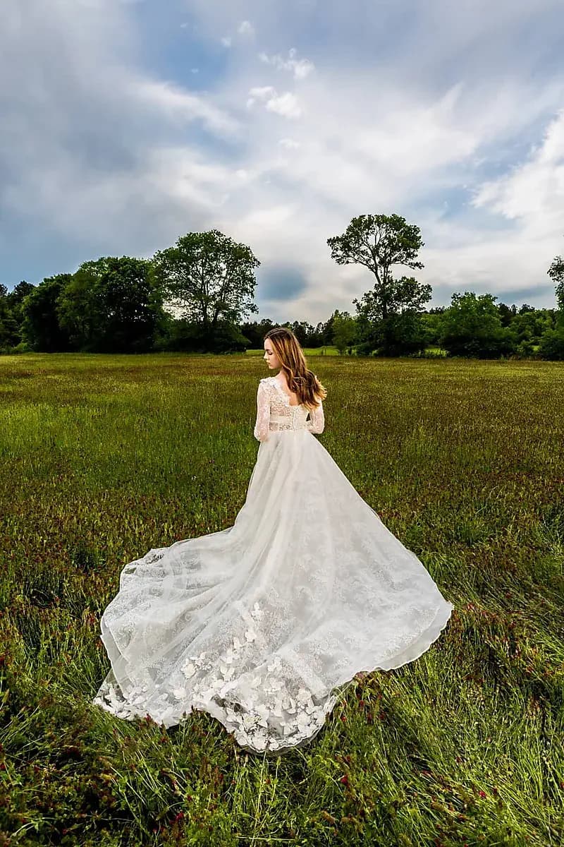 Bride in a flowing gown standing in a field