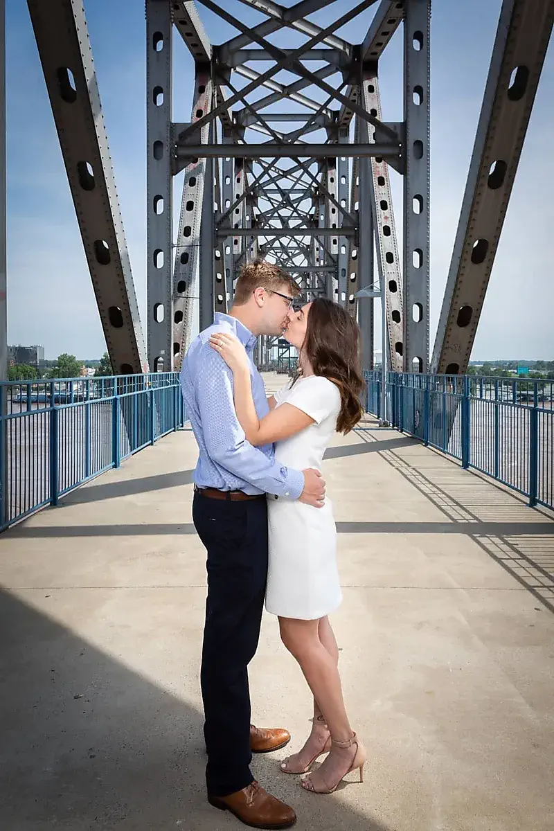 Couple kissing on a steel truss bridge