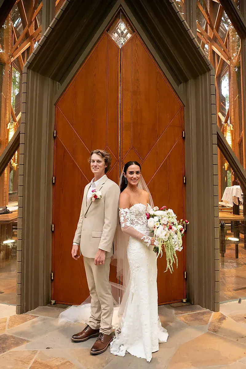 Bride and groom at the doors of a glass chapel