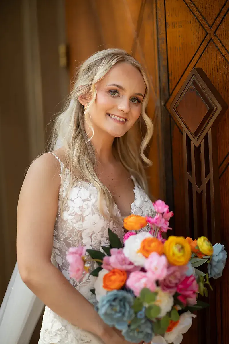Bride with a colorful bouquet at a wooden doorway
