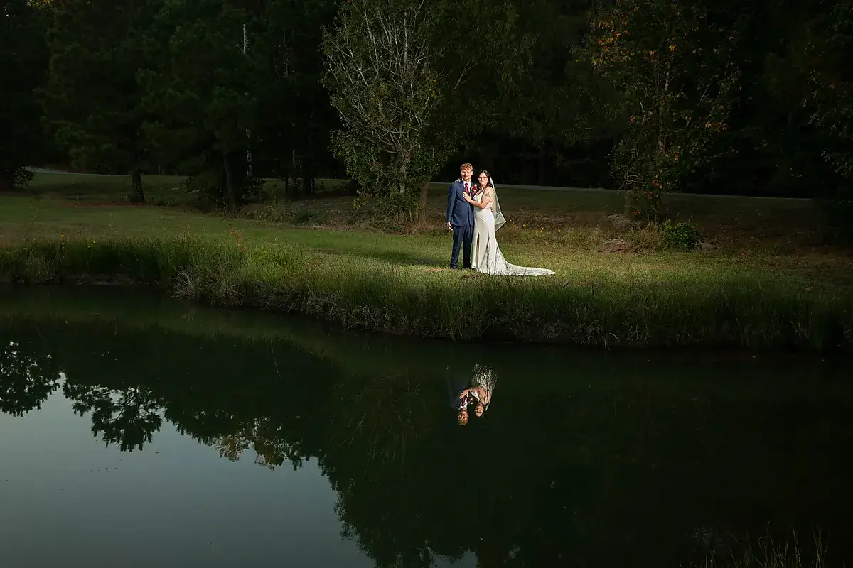 Bride and groom standing beside a reflecting pond