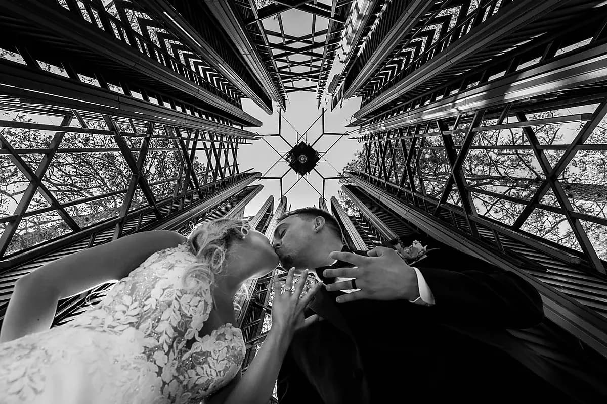Black and white portrait of the couple kissing beneath a chapel ceiling