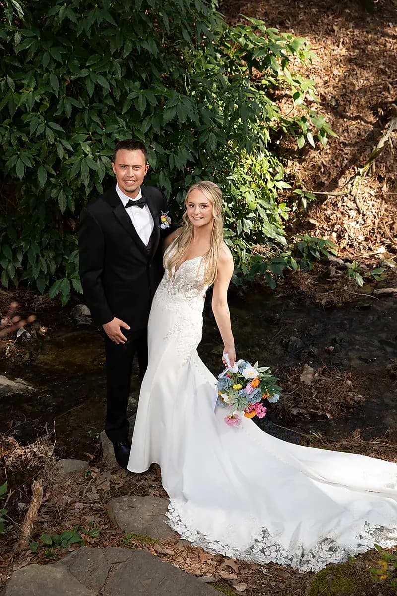 Groom and bride by a wooded creek